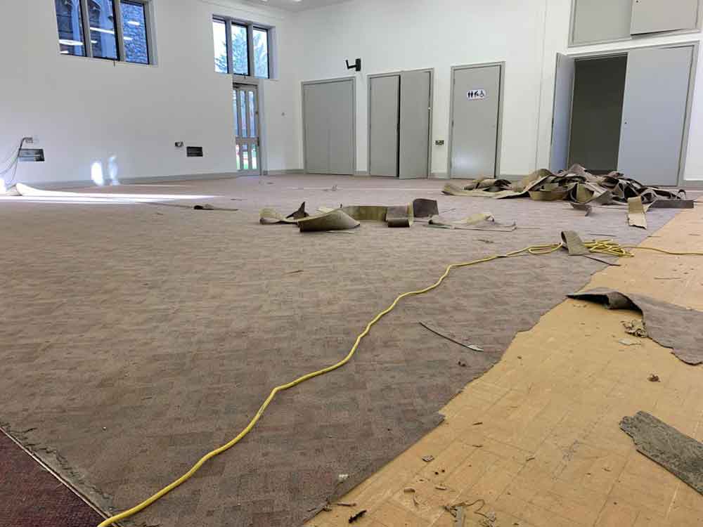 Work in progress to remove old floor covering in church in Guildford