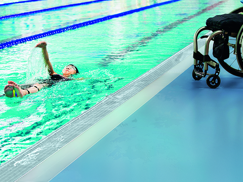 Swimmer with wheelchair alongside pool on Polyflor safety flooring